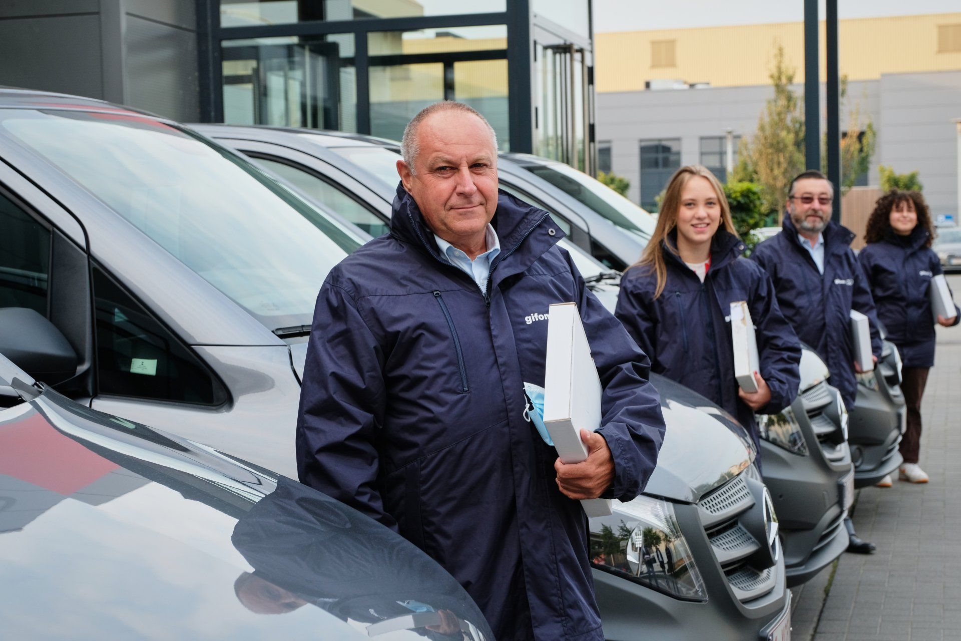 Drivers stand next to their cars with a box of keys in their hands.