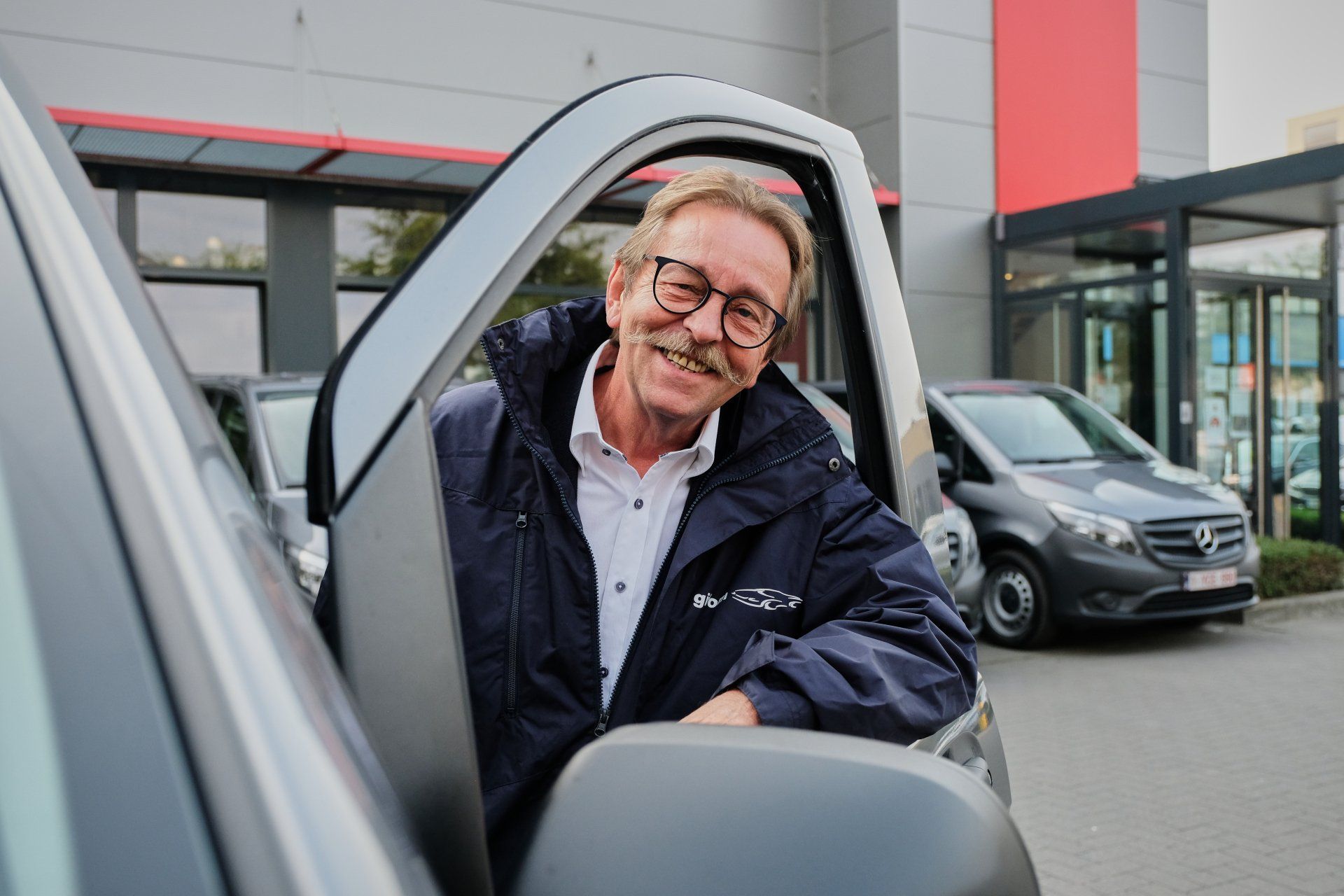 Photo of a driver smiling through the carwindow.
