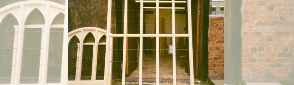 A building interior visible through a light-colored arched window frame and a set of vertical wooden supports.