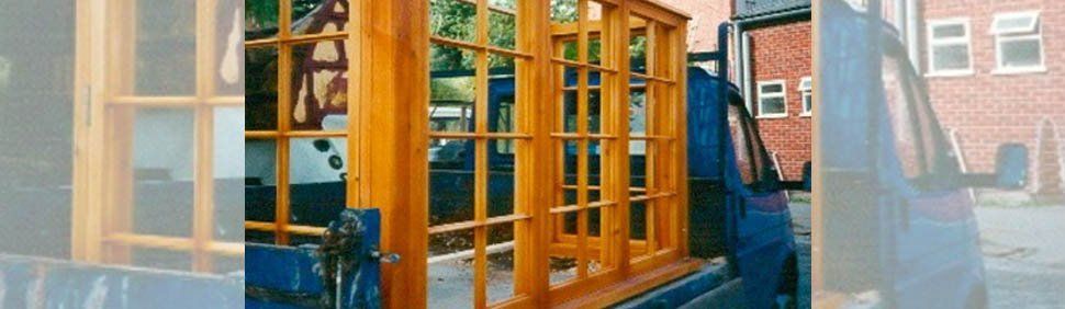 Wooden window frames loaded onto the back of a blue truck.