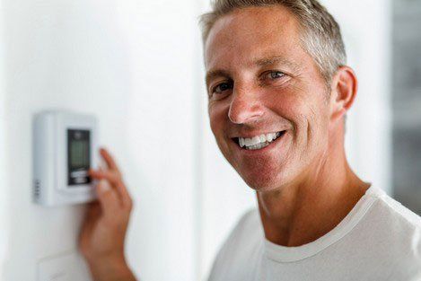 Man adjusting thermostat Man adjusting thermostat