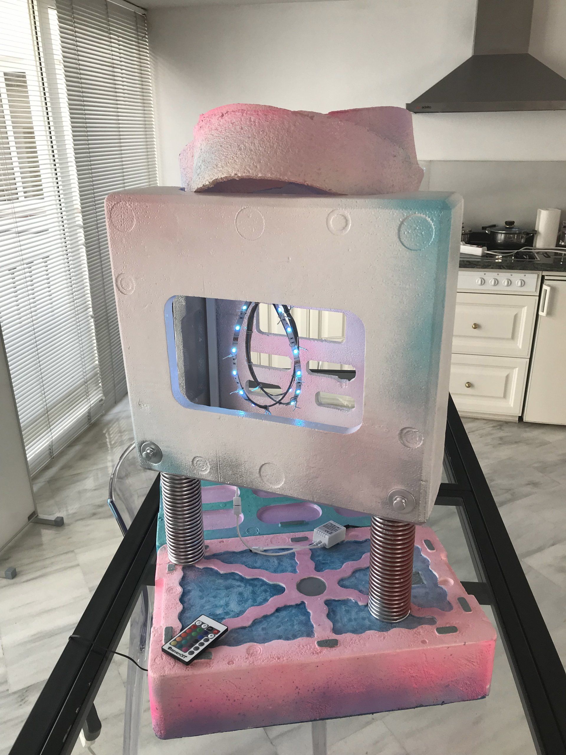 Eine rosa und blaue Skulptur steht auf einem Glastisch in einer Küche.