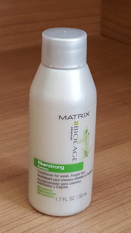 Kleine weiße Matrix Biolage Shampooflasche auf einer Holzoberfläche.