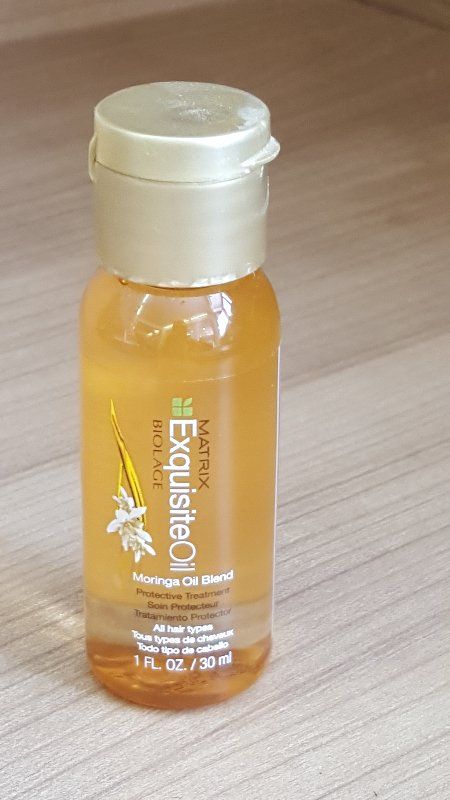 Flasche Matrix Biolage Exquisite Oil Haarpflegeprodukt, goldene Flüssigkeit, weißer Deckel, Etikett mit Blumenmuster.