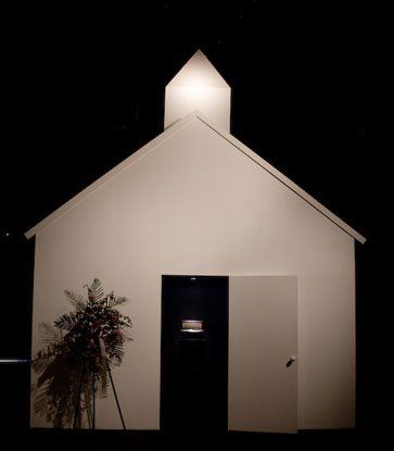 A small white church is lit up at night