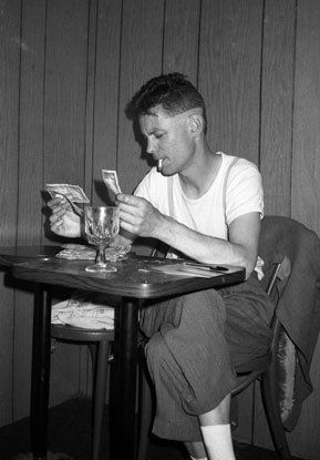 A black and white picture of a man sitting at a table.