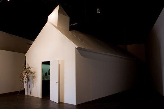 A small white house with a door open in a dark room