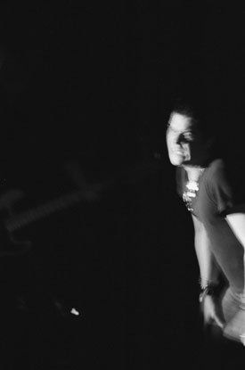 A black and white photo of a man holding a microphone in a dark room.