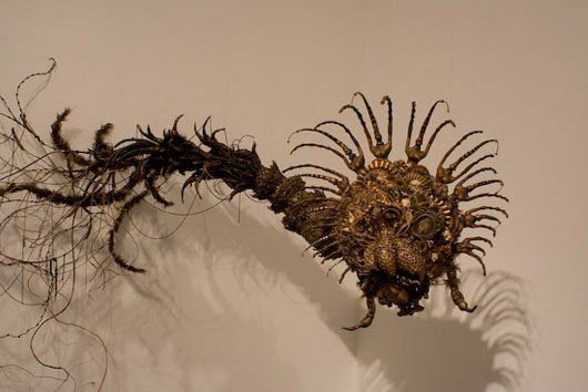 A close up of a sculpture of a spider on a white surface.
