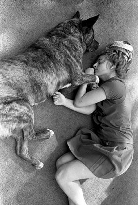 A woman is laying on the floor with a large dog