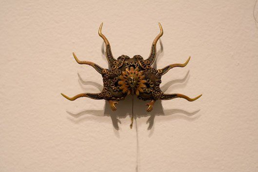 A sculpture of a spider is hanging on a white wall