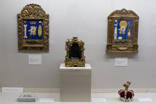 Three paintings and a crown are on display in a museum.