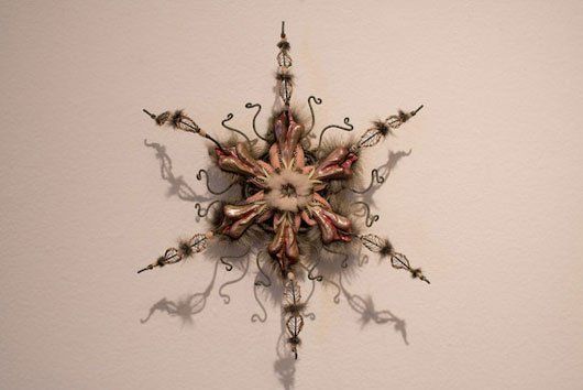 A snowflake shaped decoration is hanging on a white wall.