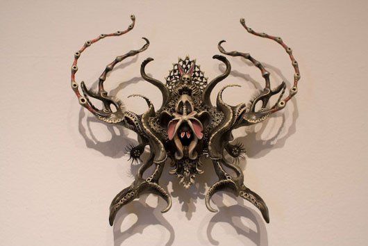 A sculpture of an octopus is hanging on a white wall