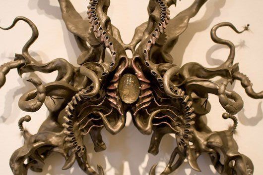 A sculpture of an octopus with tentacles is hanging on a wall