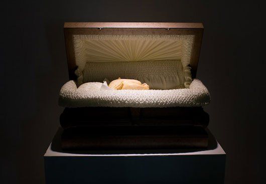 A coffin with the lid open is sitting on top of a table.