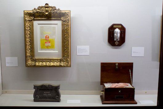 A painting is hanging on a wall next to a telephone and a box.