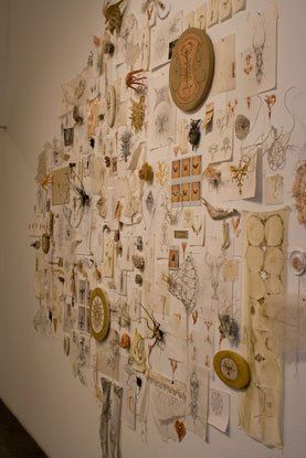 A wall filled with lots of papers and drawings on it.