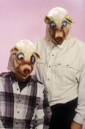 Two men wearing pig masks are standing next to each other.