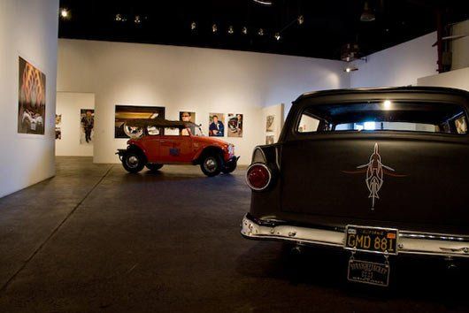 A black car with a california license plate is parked in a museum