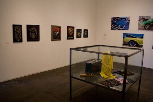 A glass case filled with various items in a room with pictures on the wall.