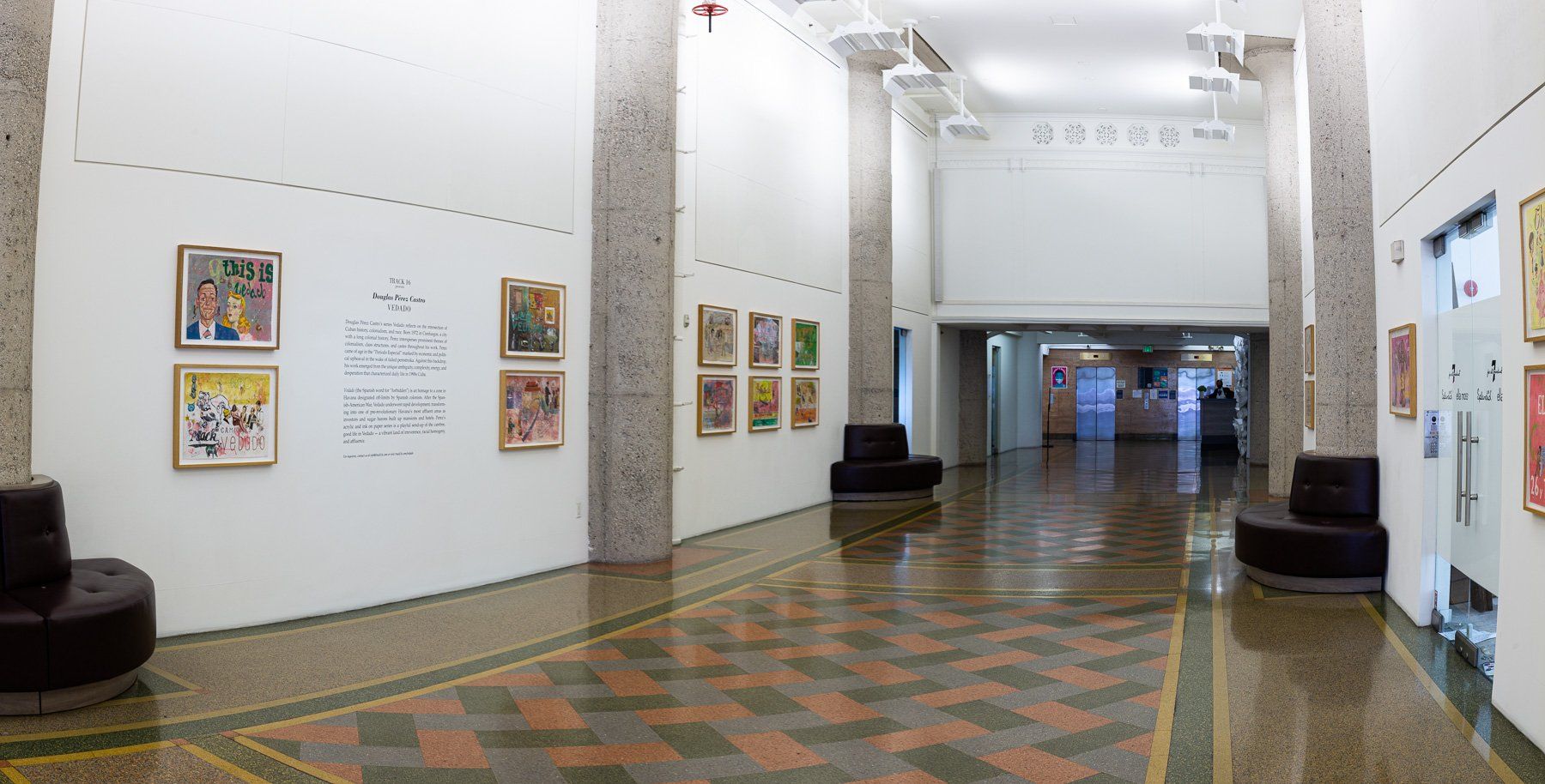 A long hallway with a checkered floor and paintings on the wall.