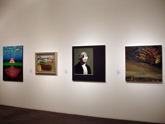 A row of paintings are hanging on a wall in a museum