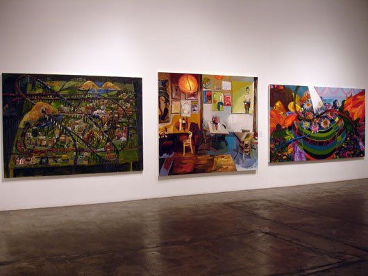 Three paintings are hanging on a wall in a room