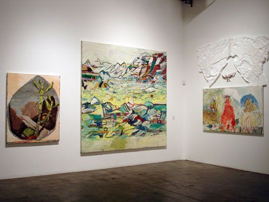 Three paintings are hanging on a wall in a room