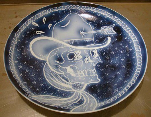 A blue and white plate with a skull wearing a cowboy hat