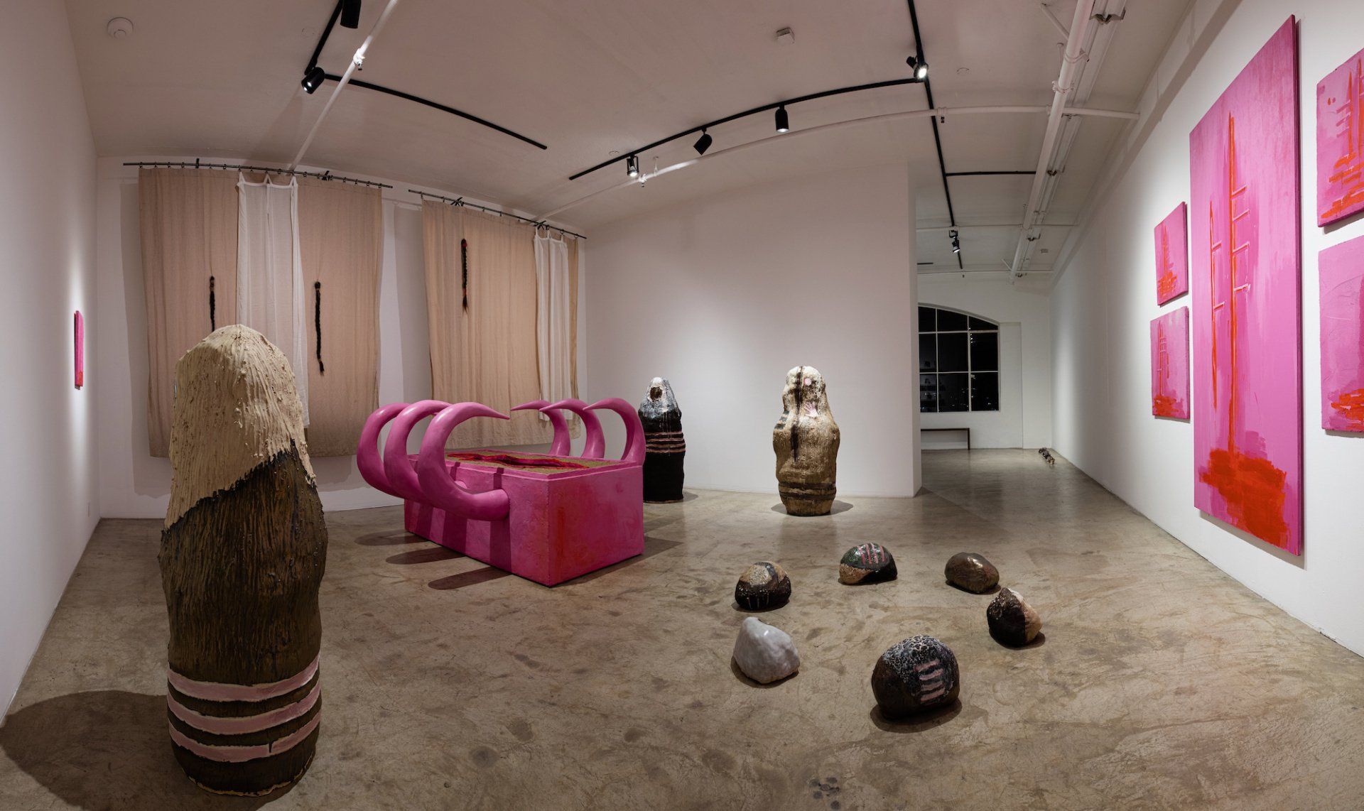 A large room with a lot of pink sculptures and paintings on the walls.