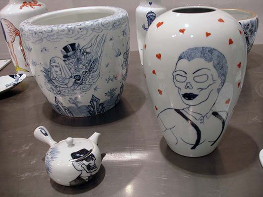 A vase with a skull on it sits on a table with other vases