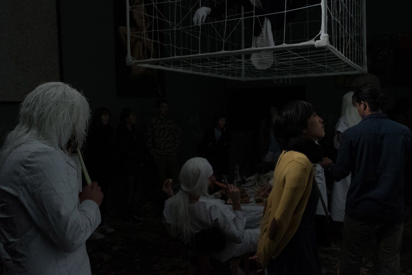 A group of people are standing around a cage in a dark room.