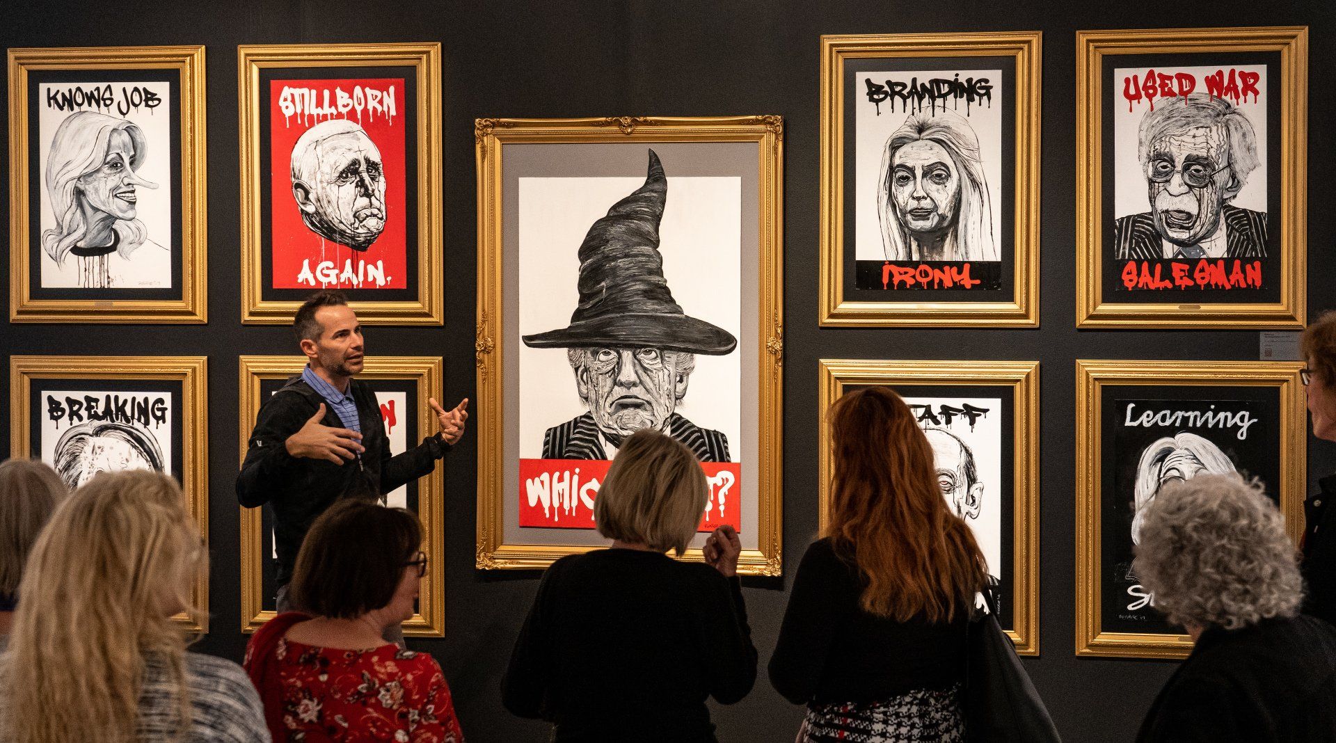 A group of people are looking at a painting on a wall.