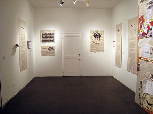 An empty room with posters on the wall and a door.