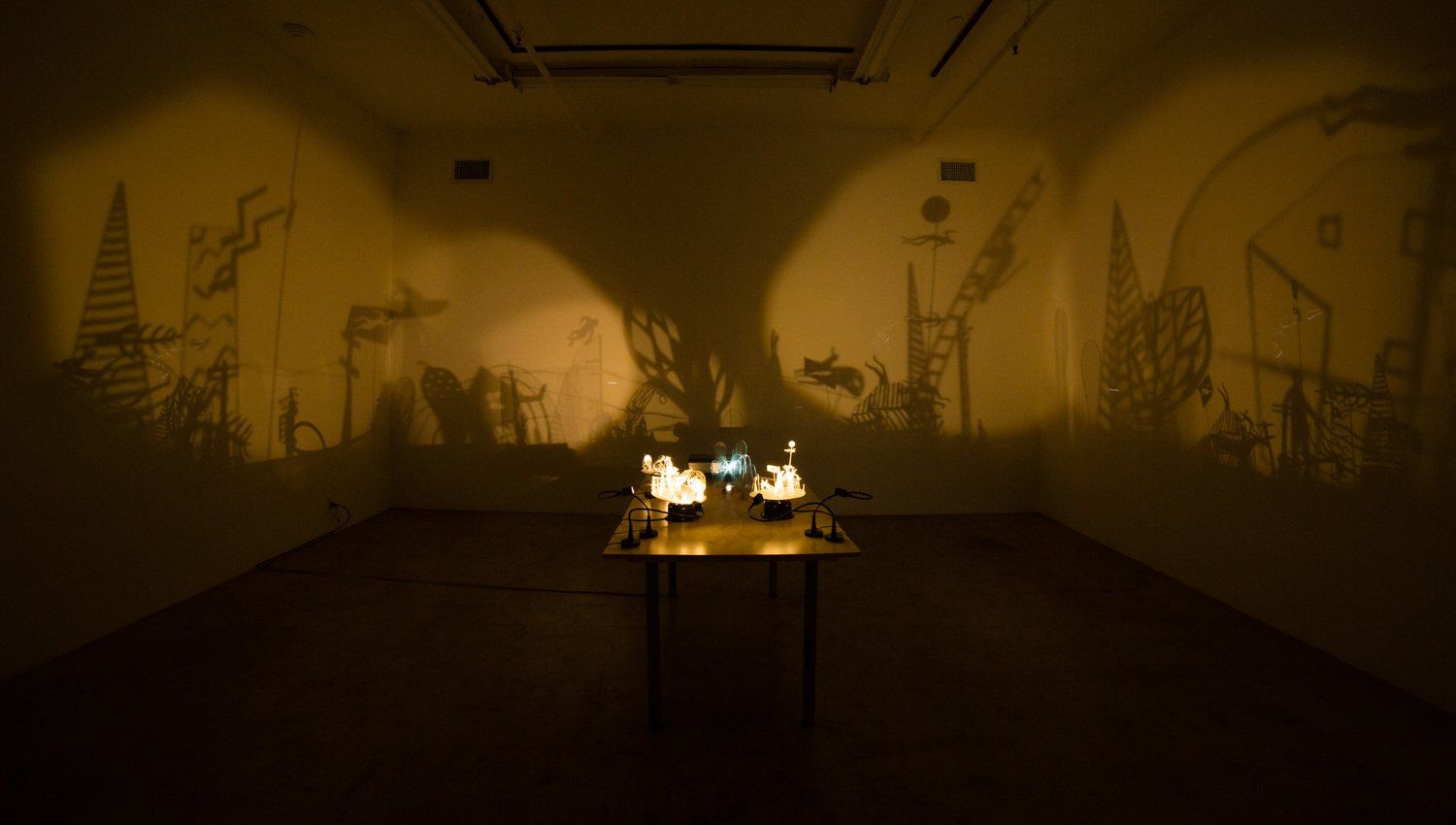 A table in a dark room with a shadow projected on the wall.