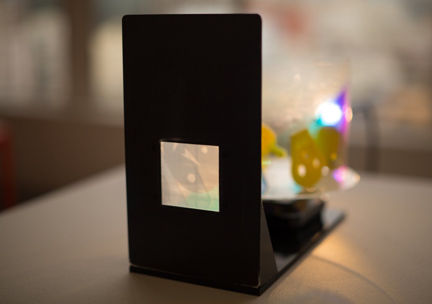 A black object with a square in the middle is on a table