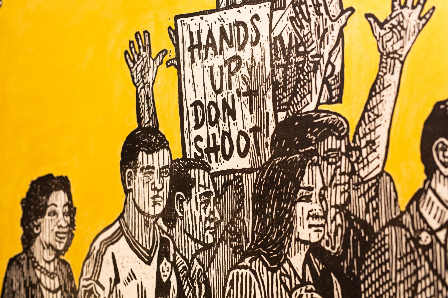 A black a white drawing of a group of people holding up a sign on a yellow background.
