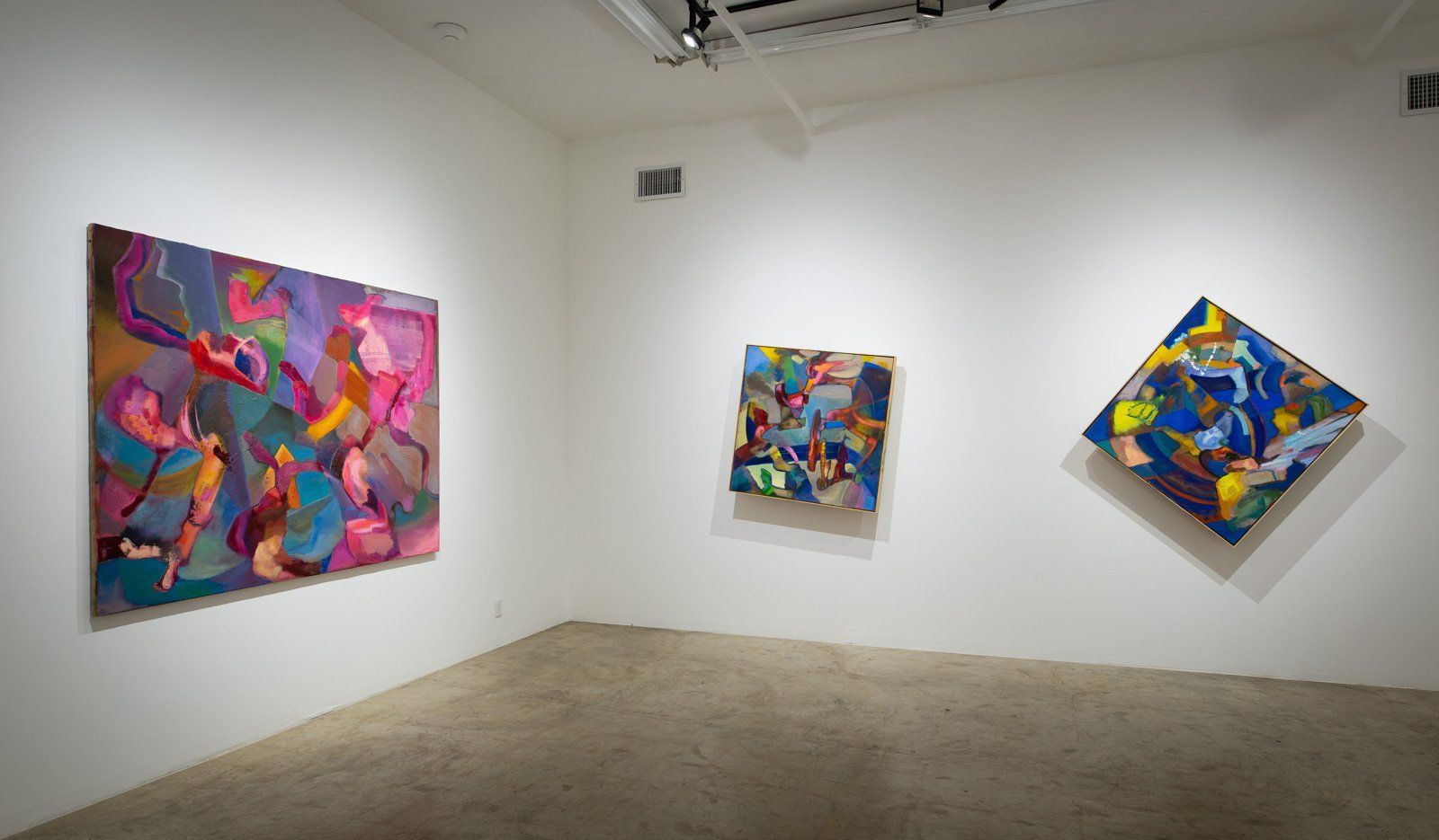 A room with three colorful paintings on the wall.