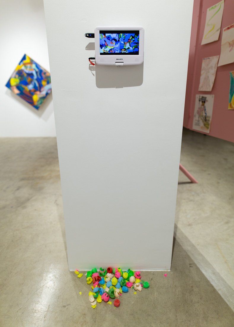 A bunch of colorful balls are on the floor in front of a wall