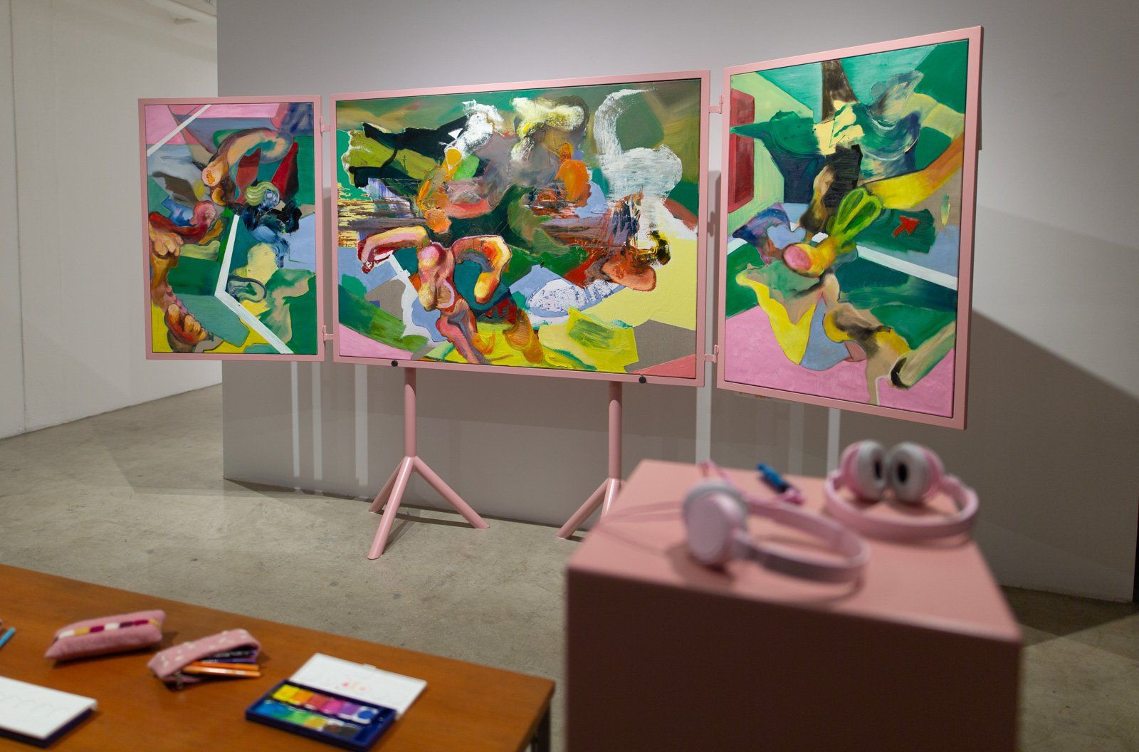 A room with three paintings and headphones on a table.