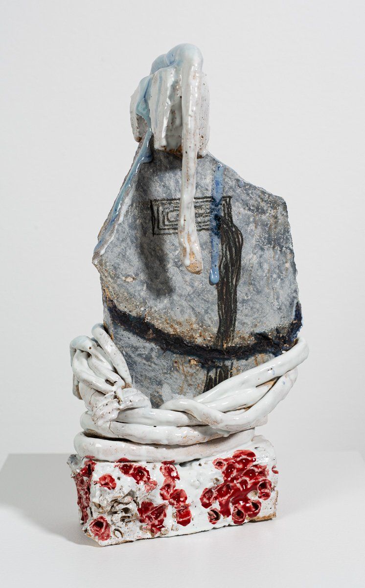 A ceramic sculpture of a rock surrounded by chains on a white surface.