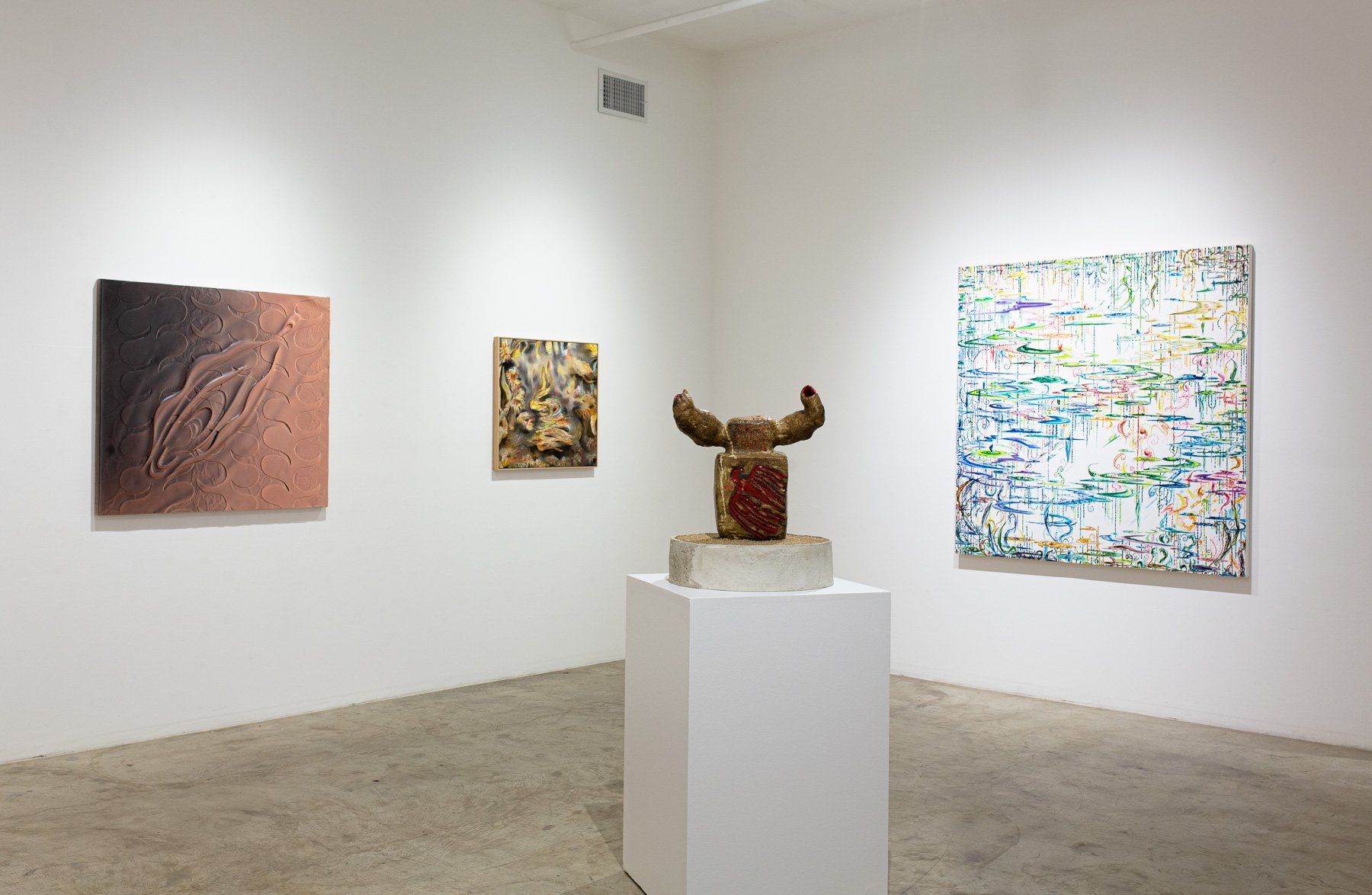 A room with a statue on a pedestal and paintings on the wall.