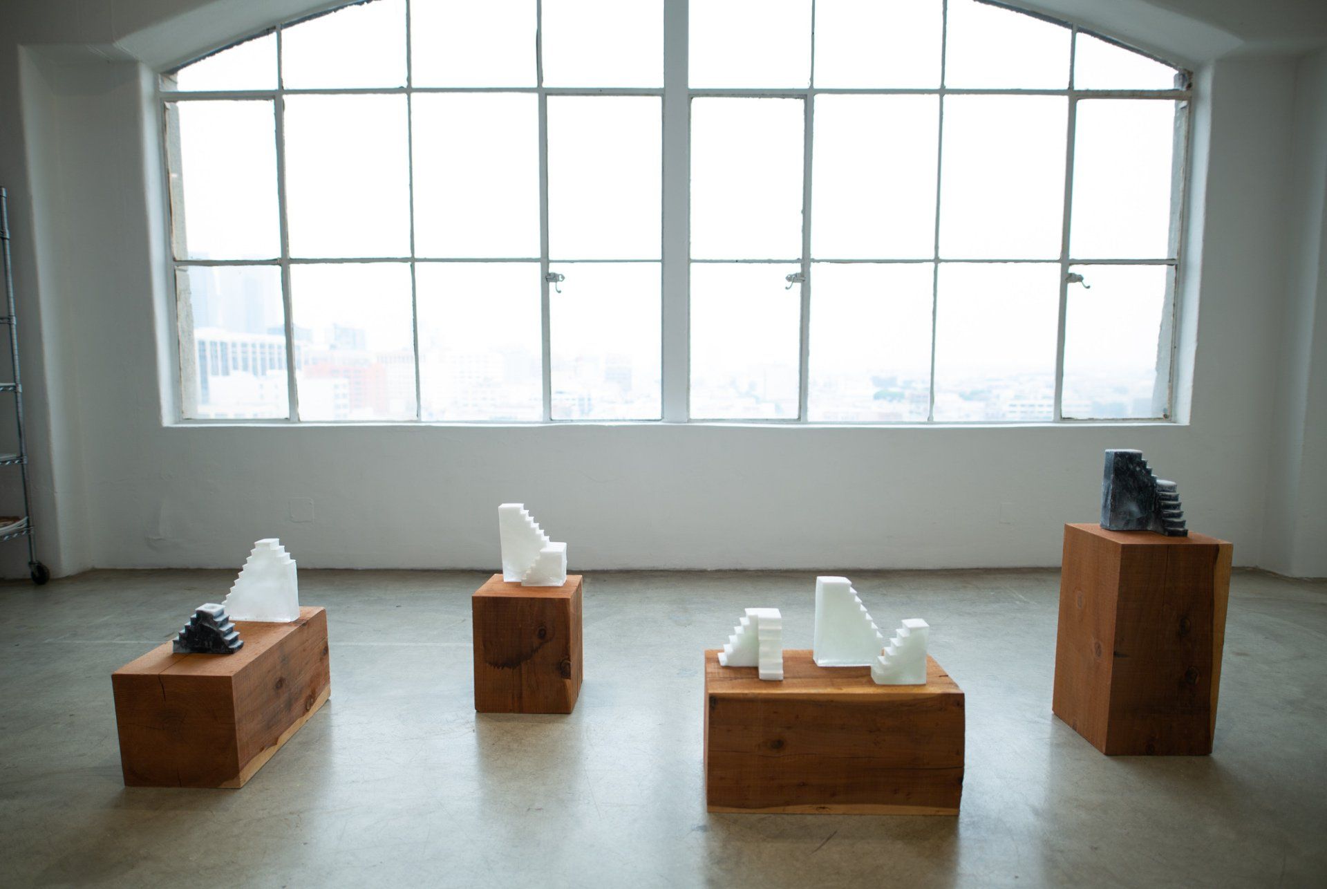 A group of sculptures are sitting on wooden blocks in front of a window.
