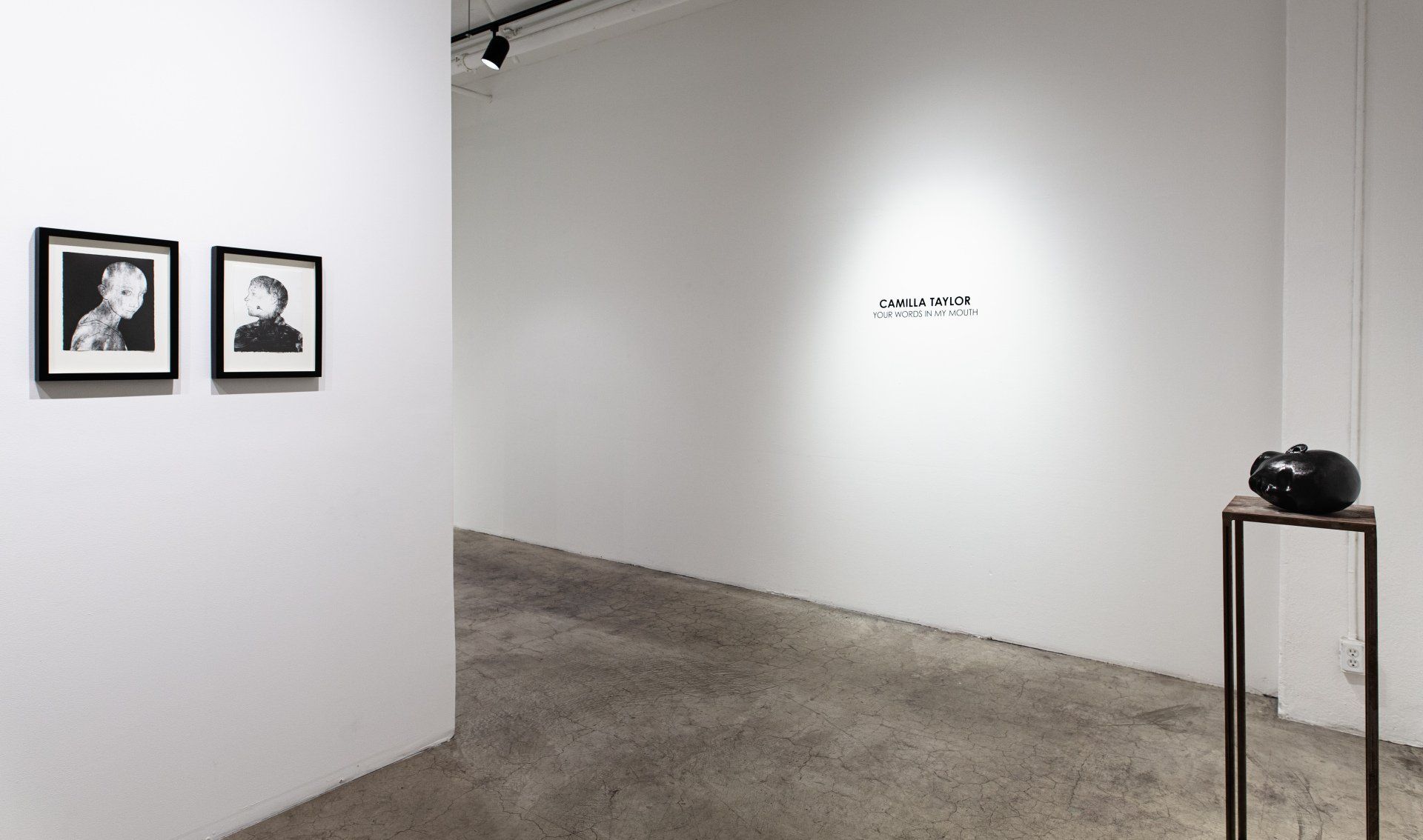A hallway with two pictures on the wall and a black object on a table.