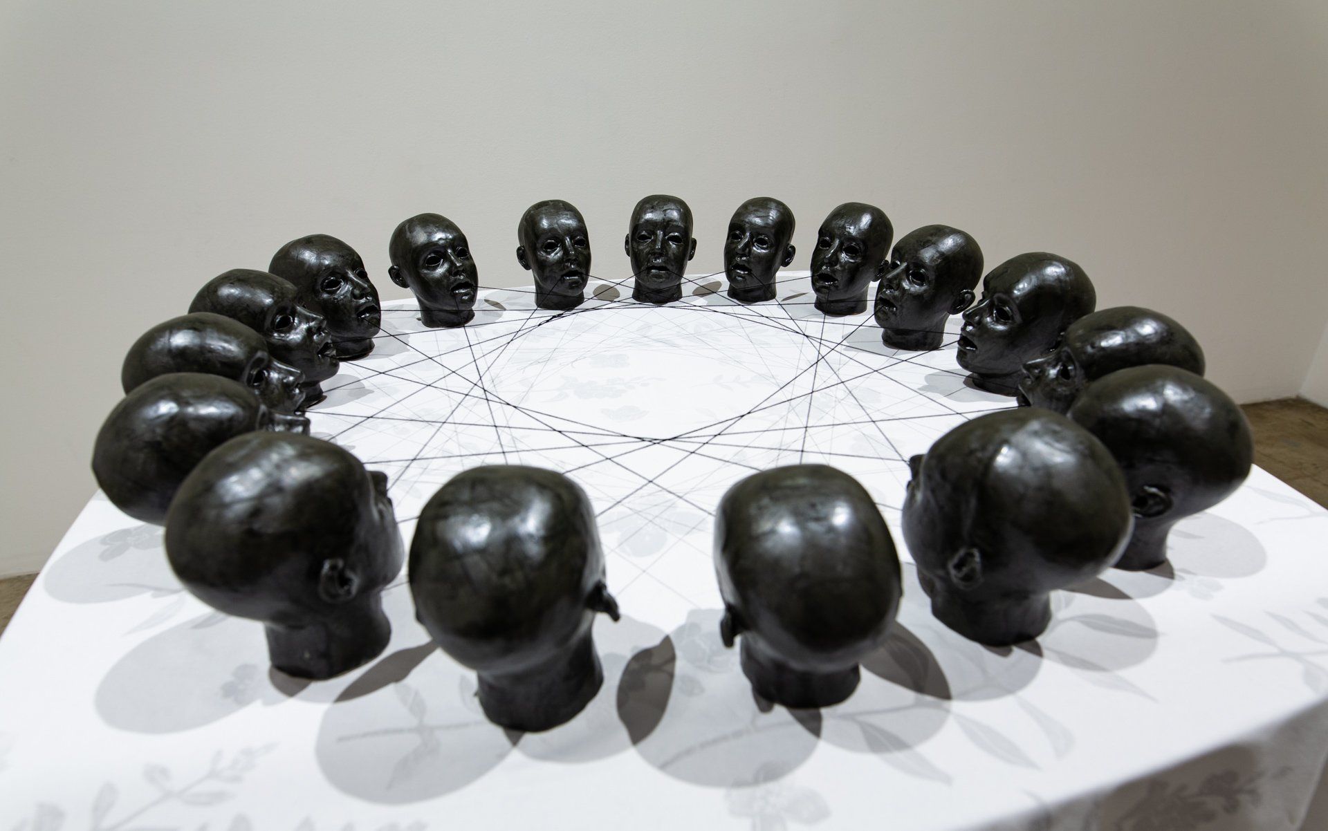 A circle of black heads sitting on top of a white table.