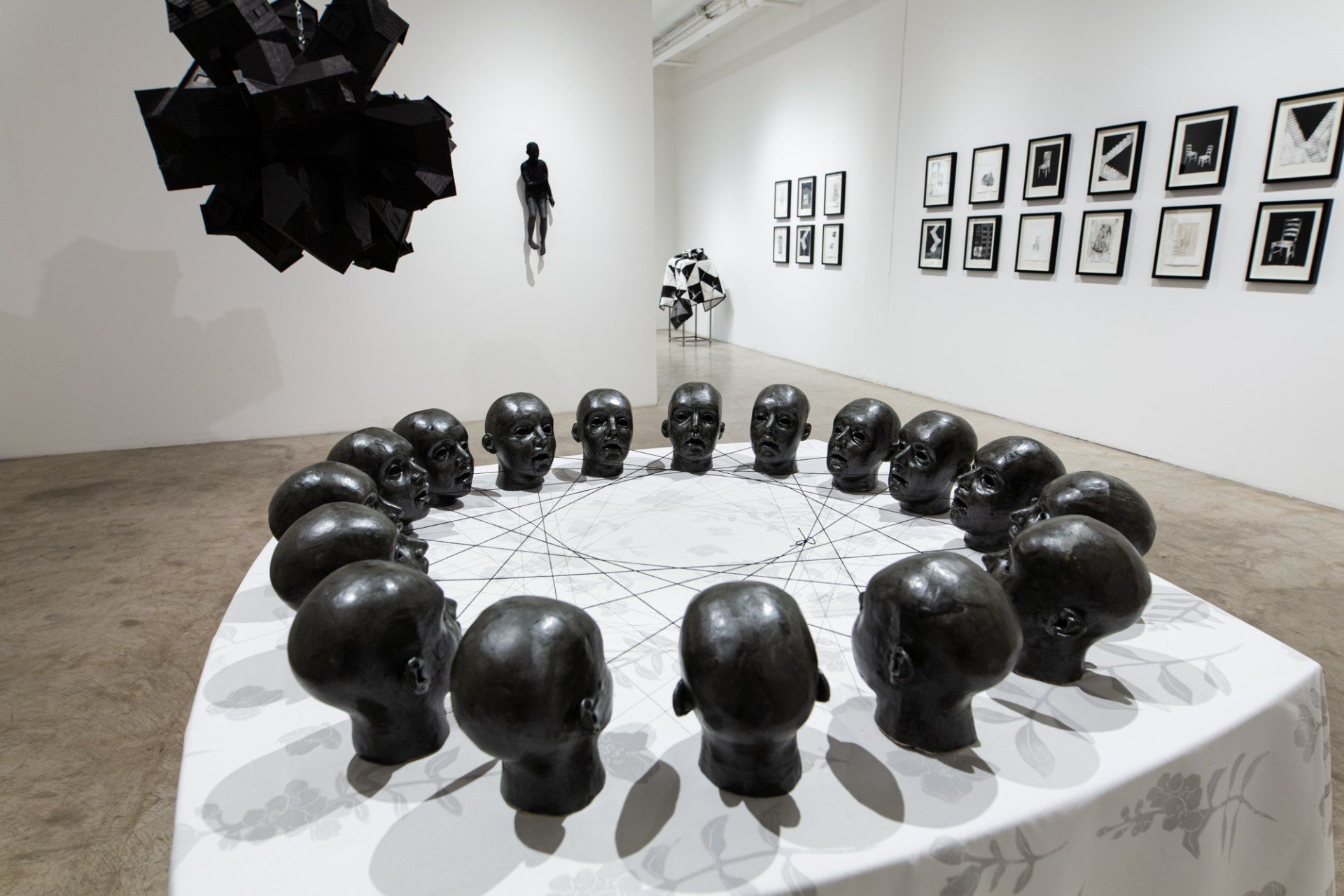 A circle of black heads are sitting on a white table in a room.