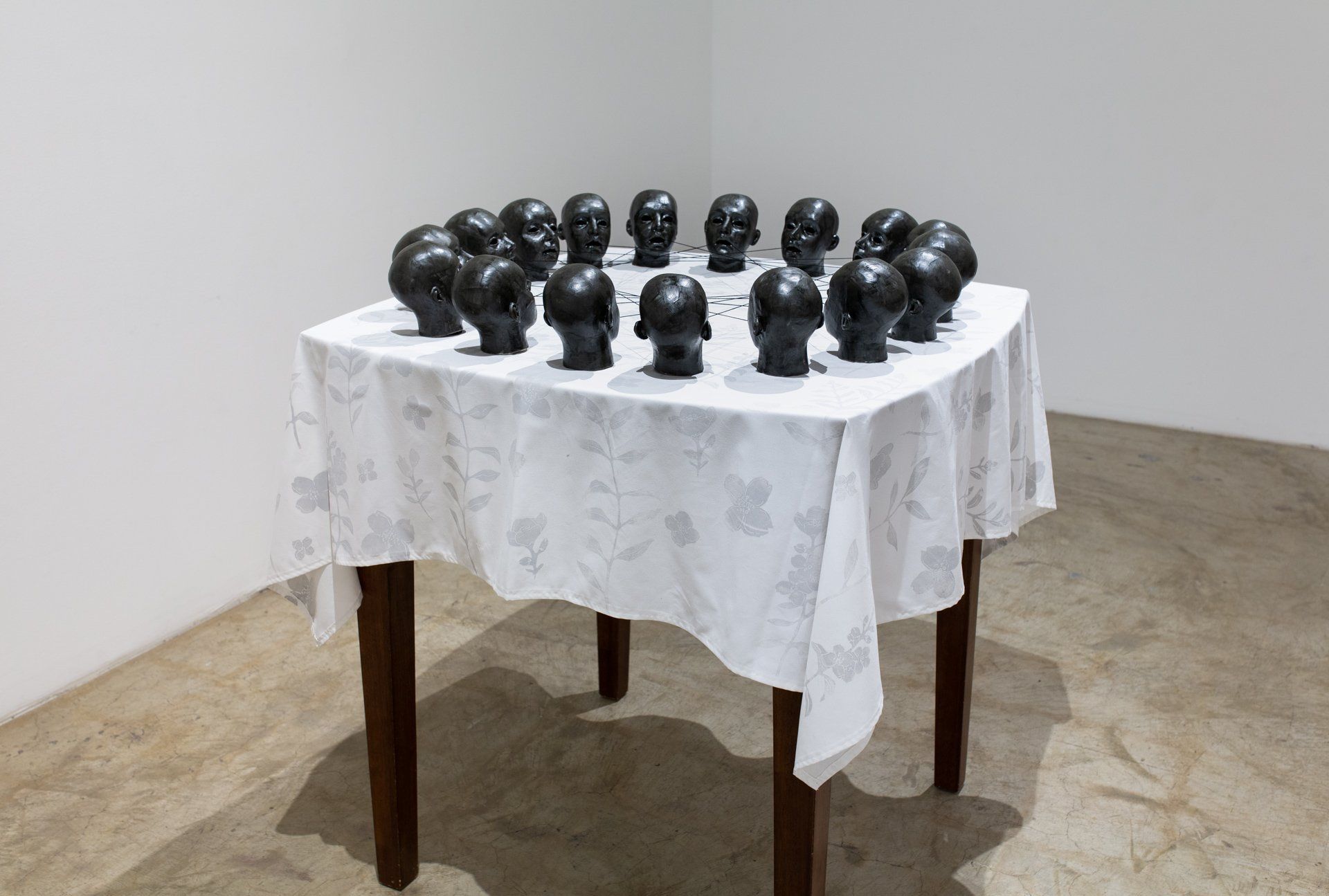A table with a white tablecloth and black heads on it.
