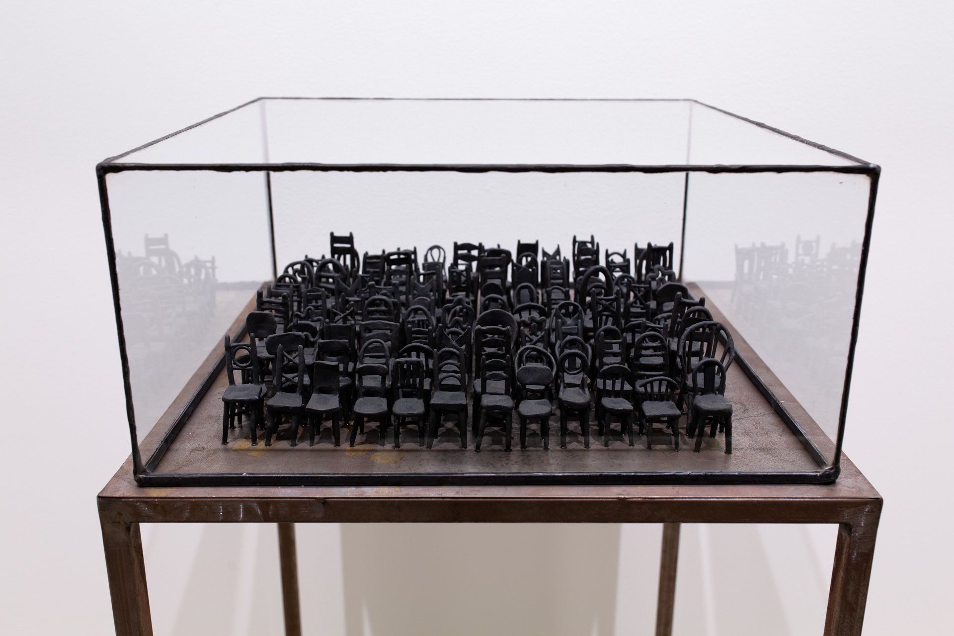 A glass display case filled with black chairs on a wooden table.