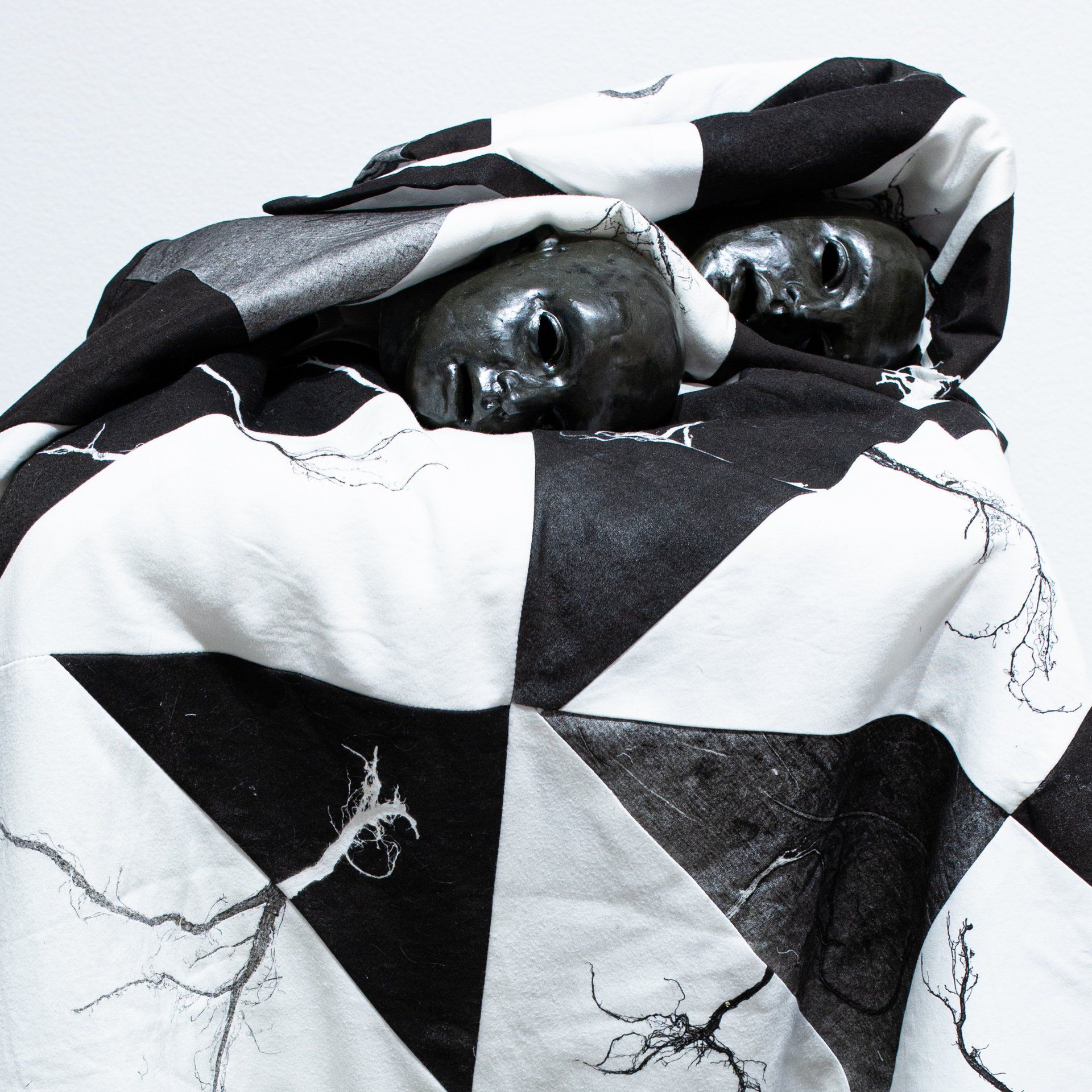 Two skulls are wrapped in a black and white blanket